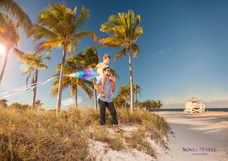 lifestyle photography of father and son flying kite at beach on sunny day