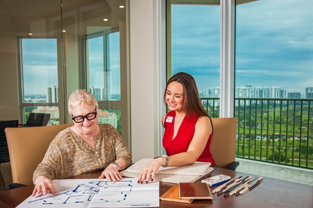 lifestyle-photography-of-senior-woman-looking-over-floor-plans-with-younger-assistant