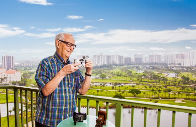 portrait-photography-of-senior-man-with-vintage-camera-on-balcony-overlooking-aventura-florida