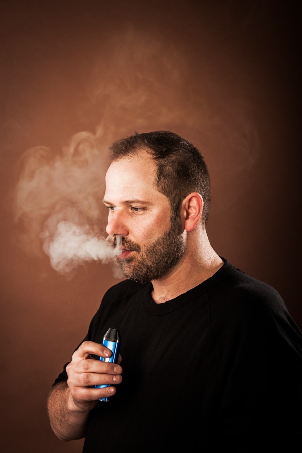 portrait photography of Jan Verleur blowing smoke holding e-cigarette