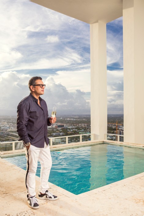 portrait photography of naeem khan standing on a pool deck high above miami